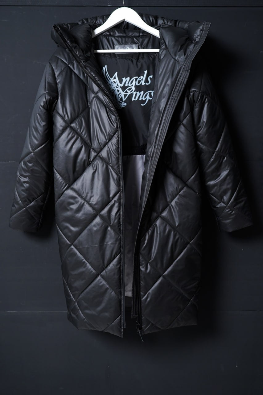 Black quilted jacket on a hanger against a dark background