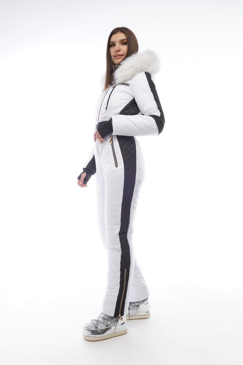 Person wearing a white and black ski suit with fur trim on a white background