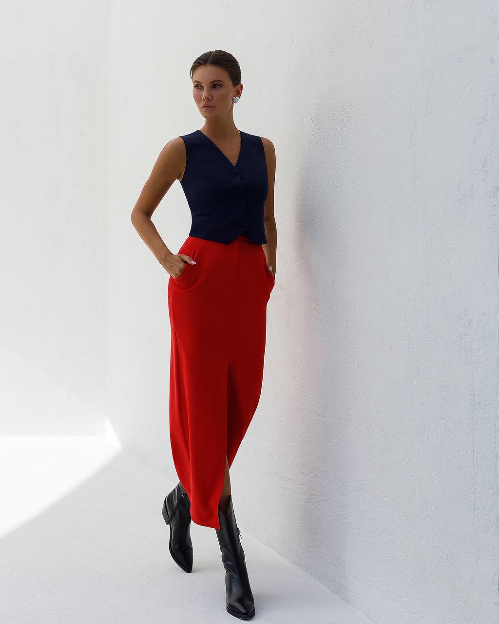 Woman wearing a navy top and red pants against a white background