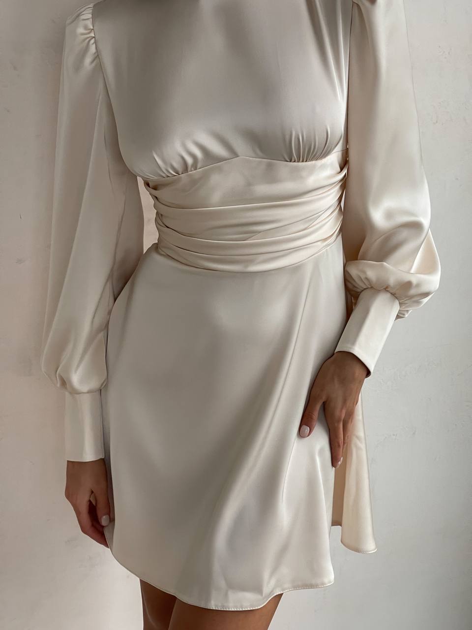 White satin dress with long sleeves on a plain background