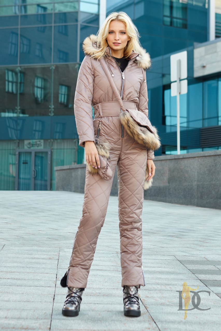 Woman wearing a beige puffer jumpsuit with fur trim in an urban setting