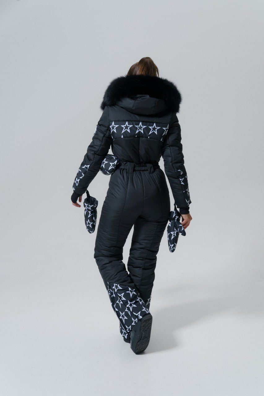 Person wearing a black snowsuit with star patterns on a white background