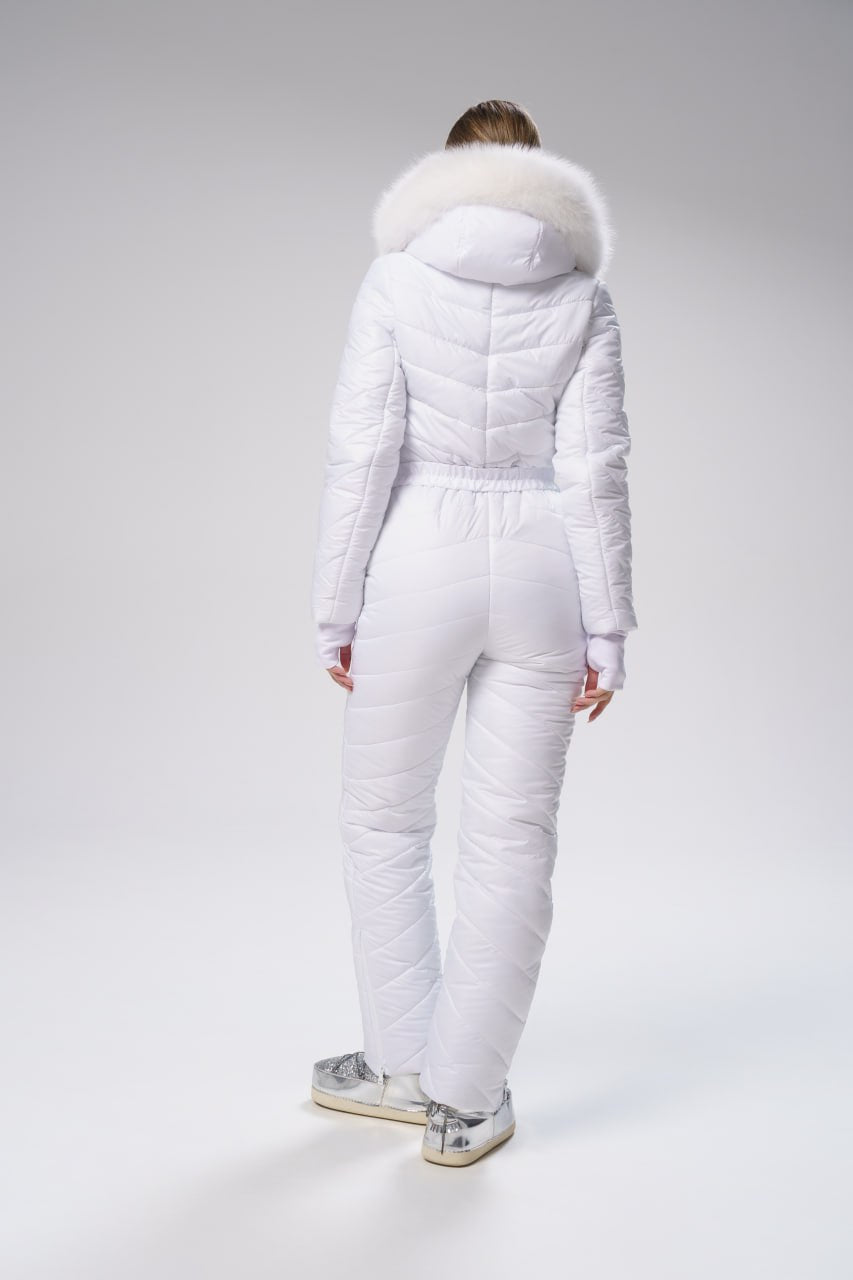 Person wearing a white puffer suit with fur hood on a gray background