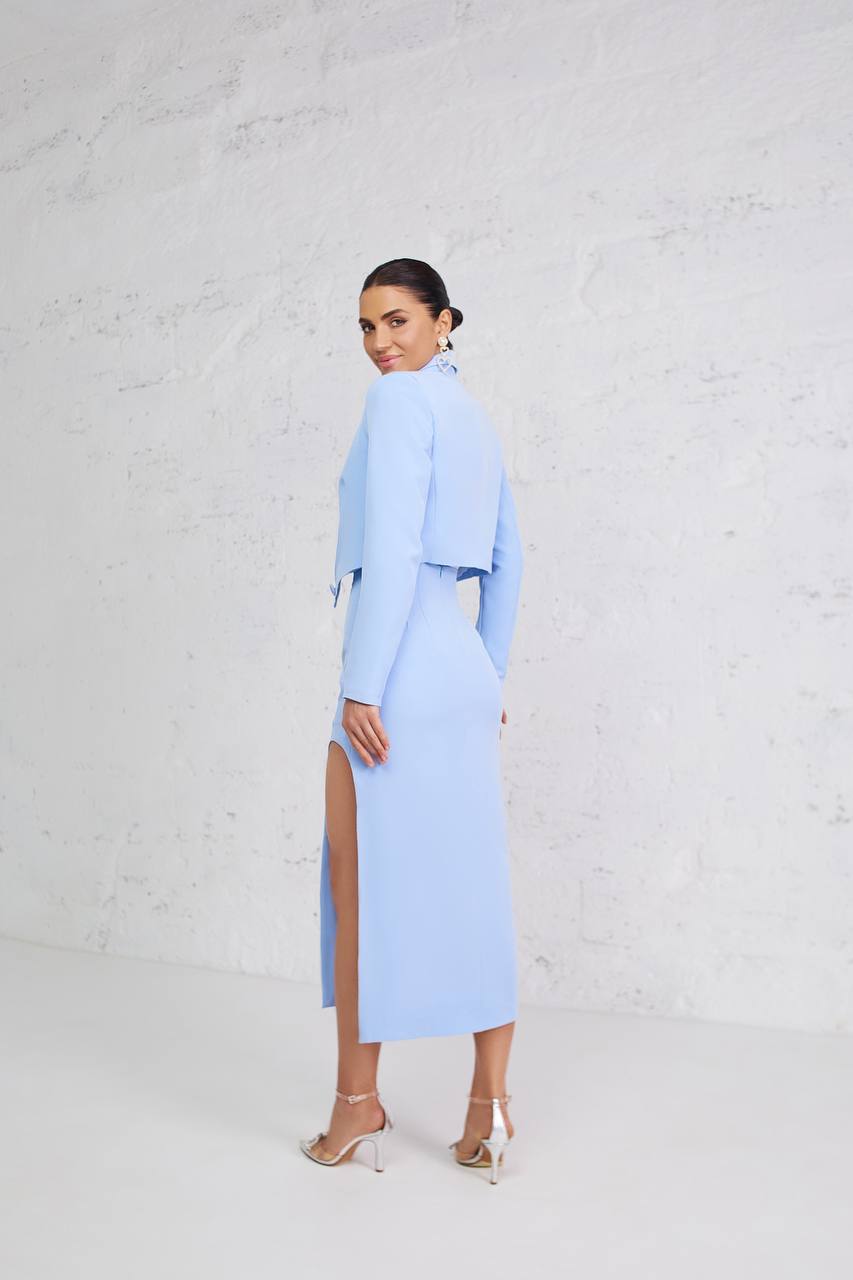 Woman wearing a light blue outfit with a slit skirt against a white background