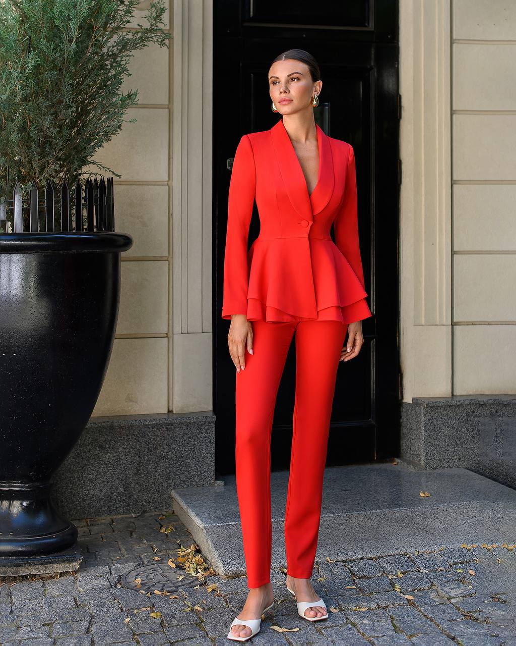 Woman in a red suit standing outside a building