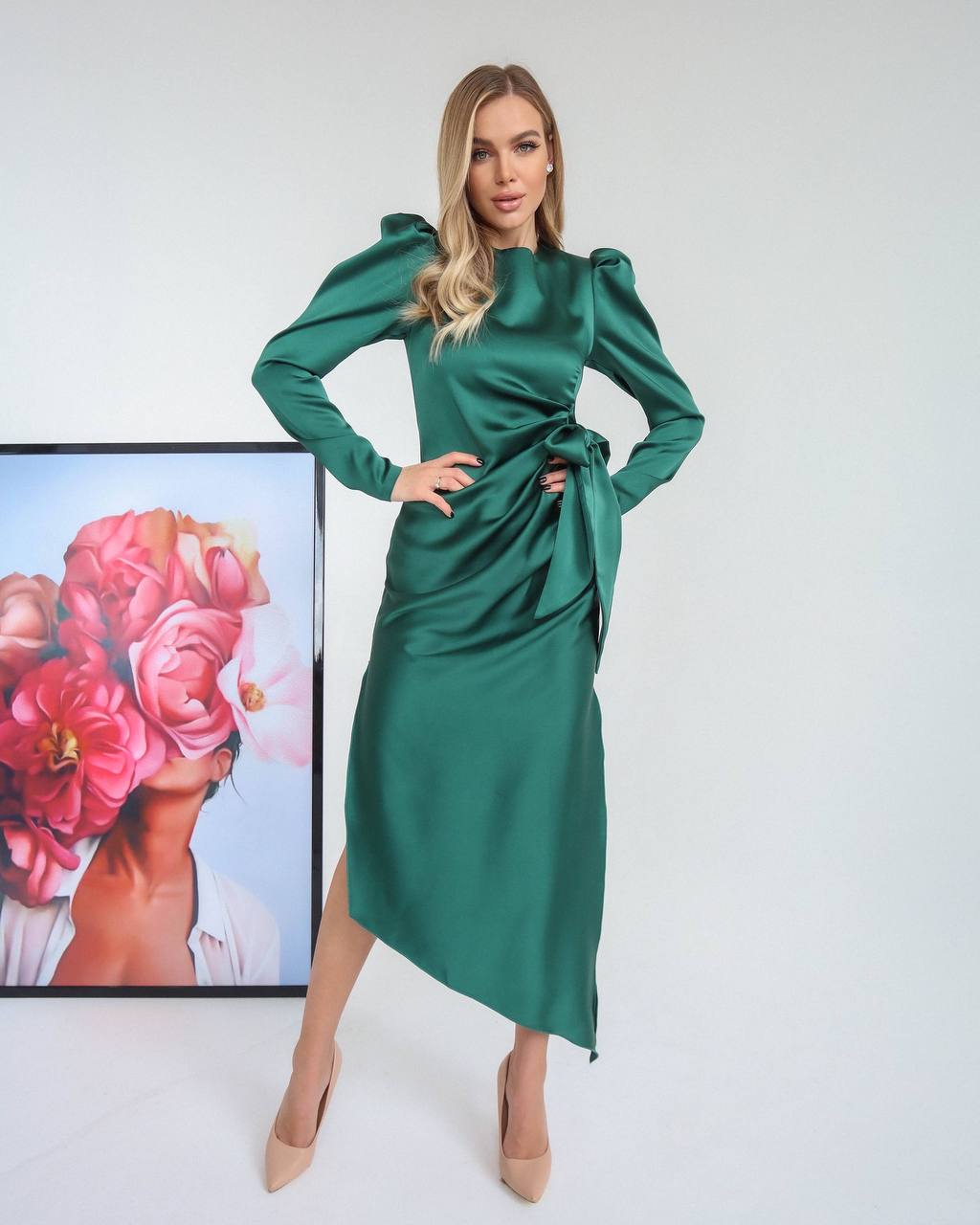 Woman wearing a green dress with a blurred floral painting in the background