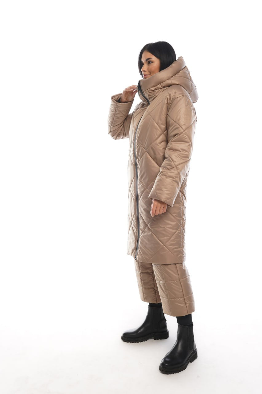 Person wearing a long beige quilted coat on a white background