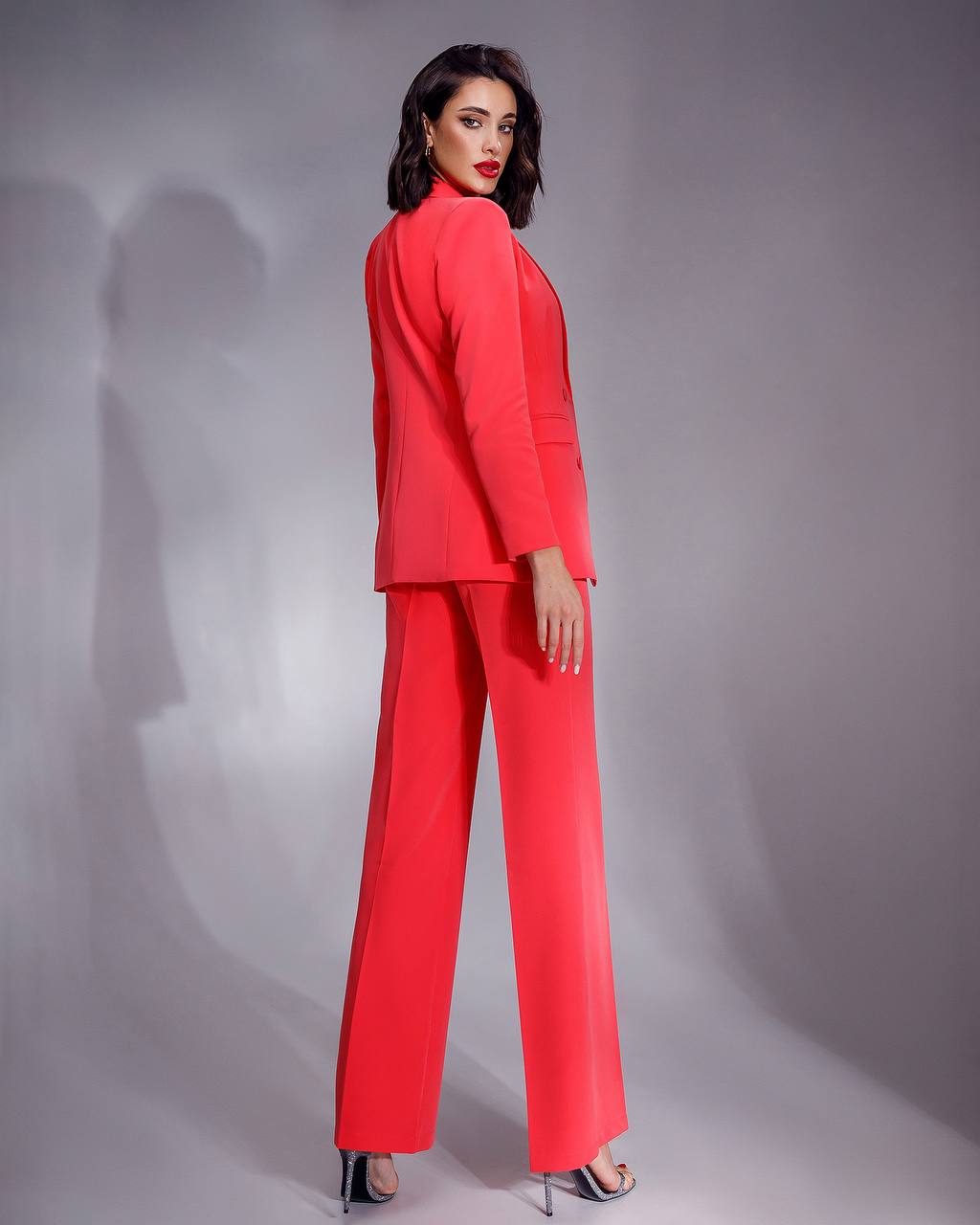 Woman wearing a red suit against a gray background