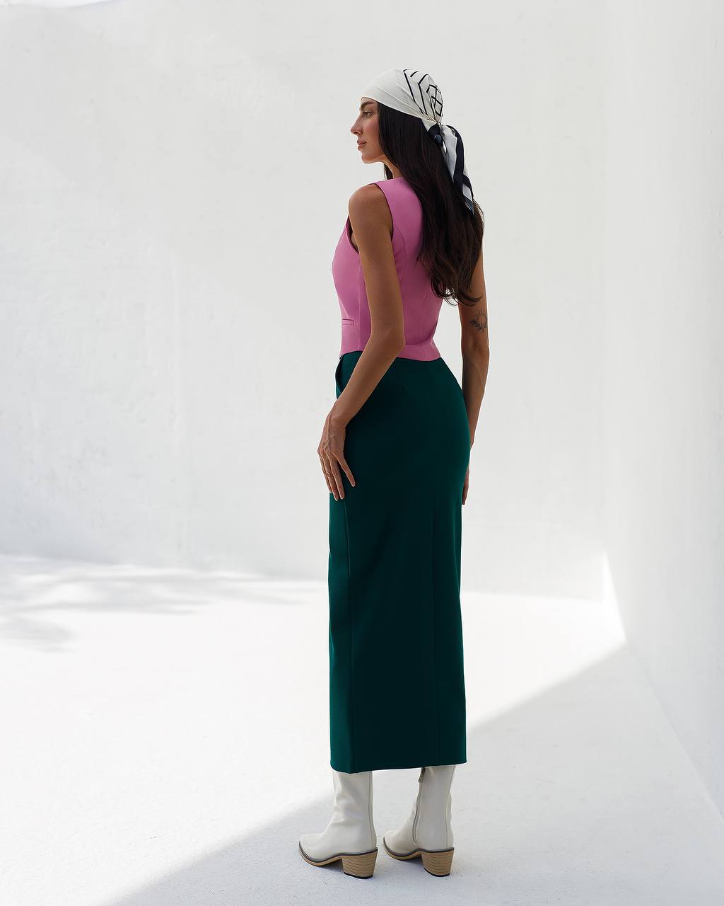 Woman wearing a pink top and green skirt against a white background
