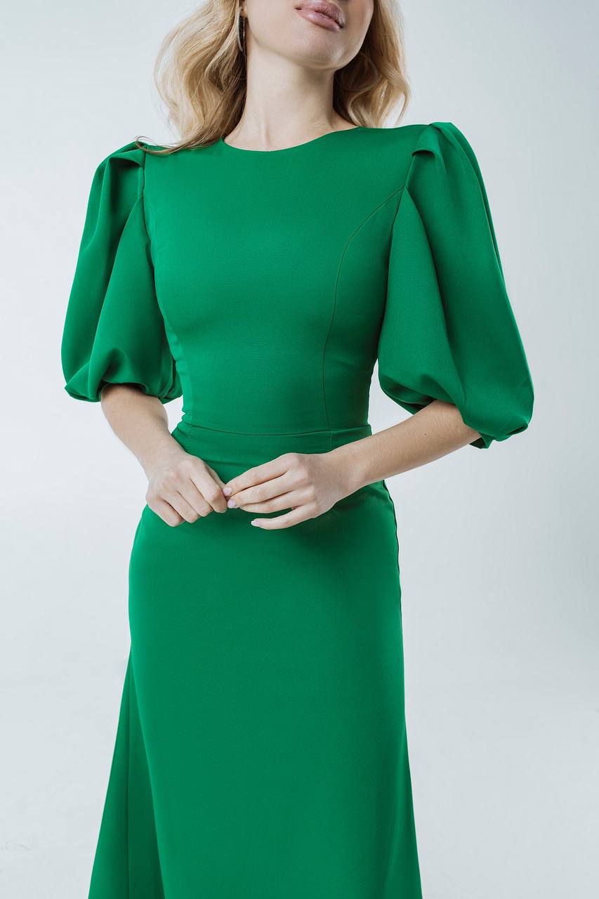 Green dress with puffed sleeves worn by a model on a white background