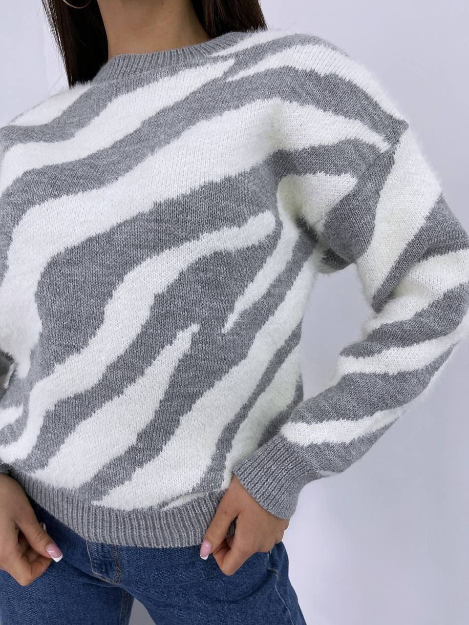 Gray and white zebra pattern sweater worn by a person on a plain background