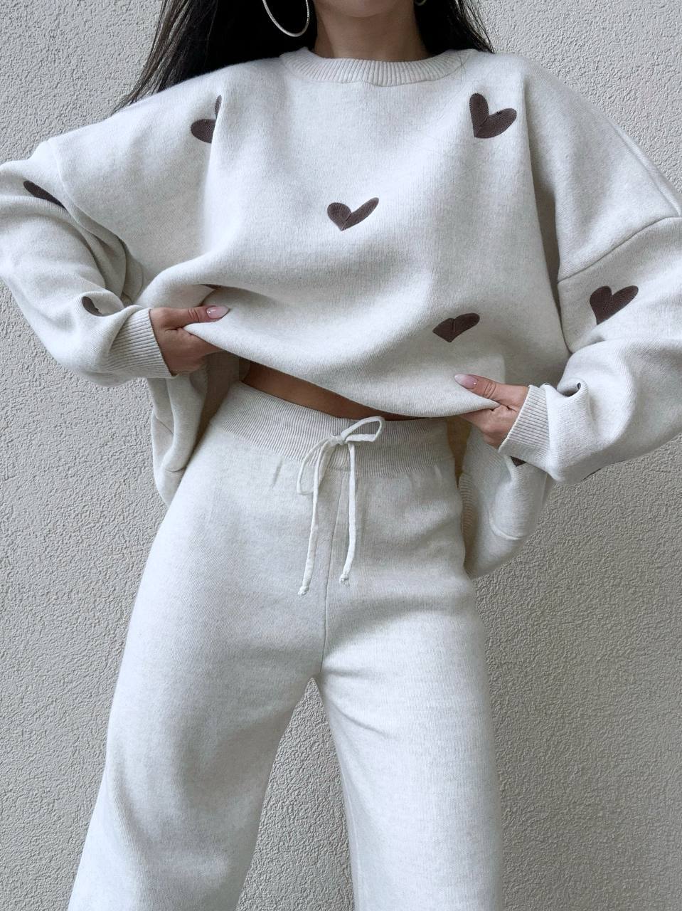 White sweatshirt and pants set with heart patterns on a plain background