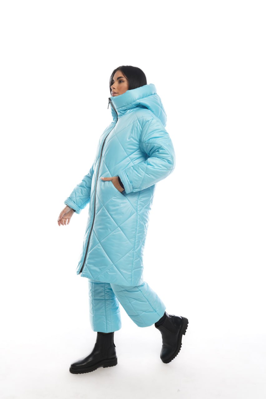 Person wearing a light blue puffer coat and pants on a white background