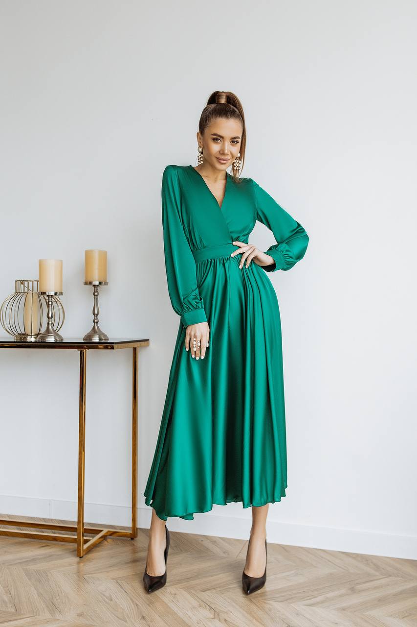 Woman wearing a green dress standing in a room with a table and candles.
