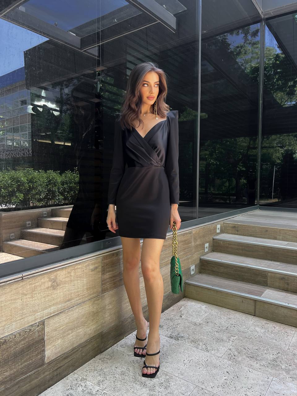 Woman in a black dress standing outdoors near a modern building.
