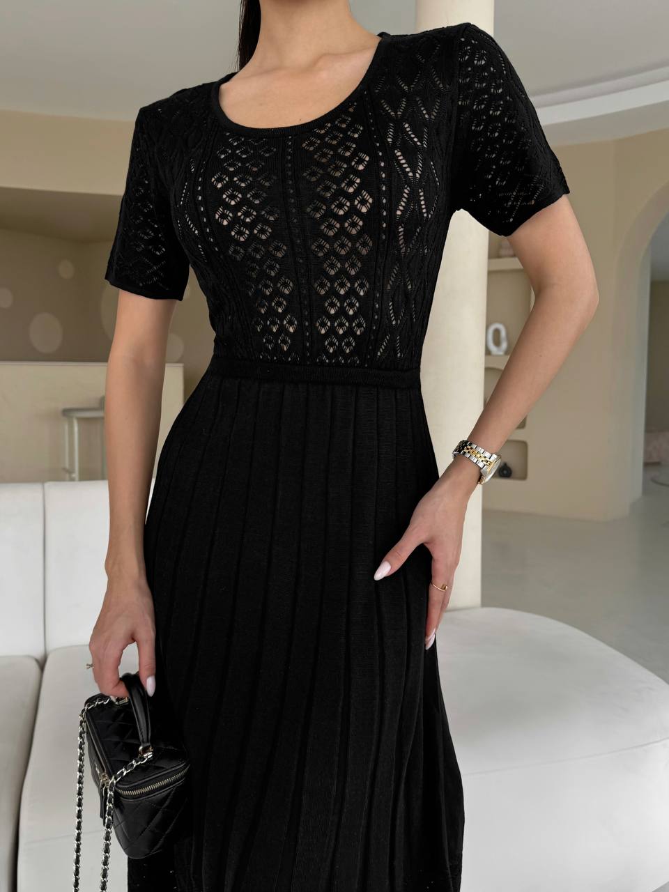 Person wearing a black dress with intricate patterns in an indoor setting