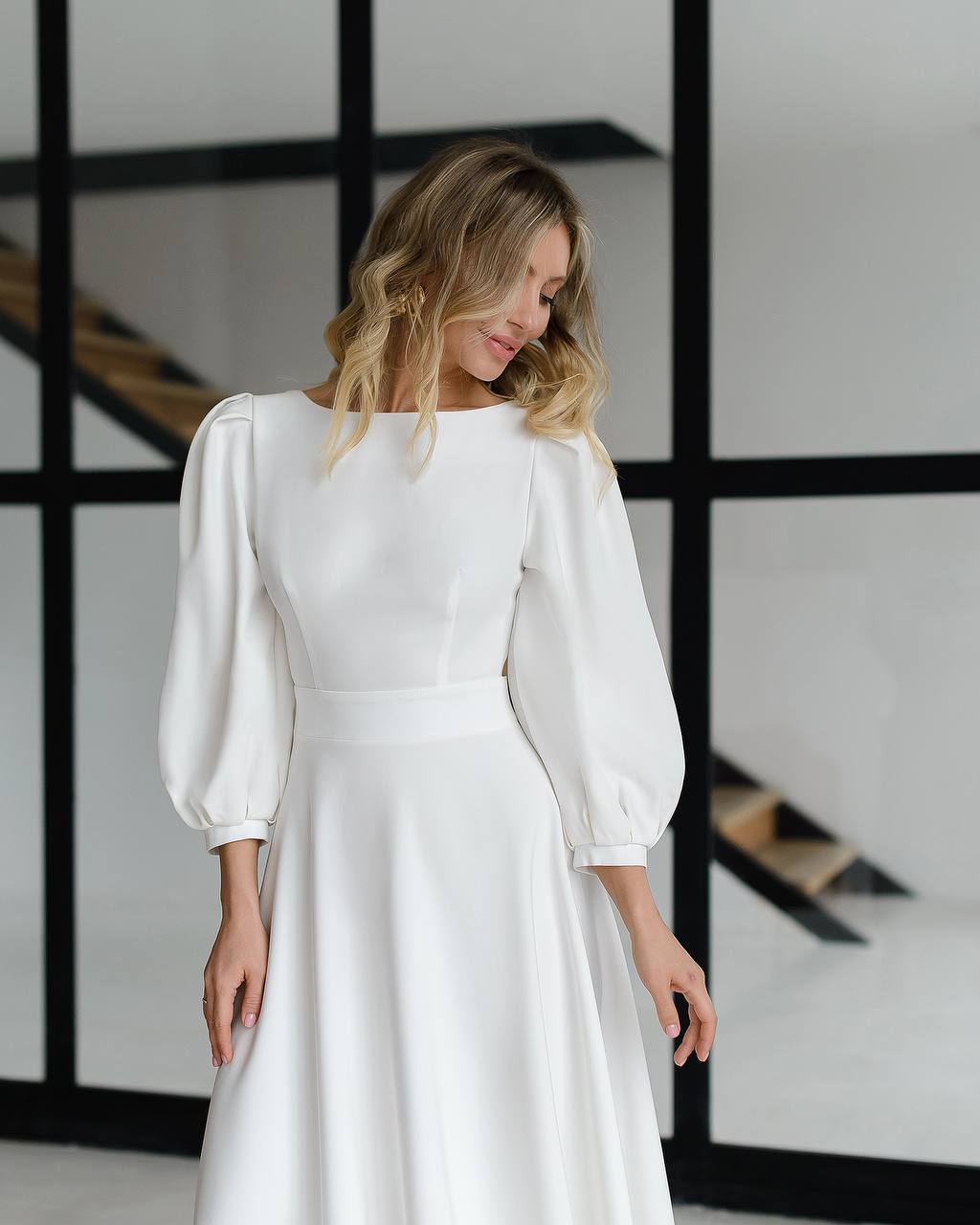 Woman wearing a white dress with puffed sleeves in a minimalistic setting
