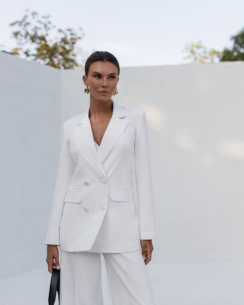 Person wearing a white suit standing against a light background