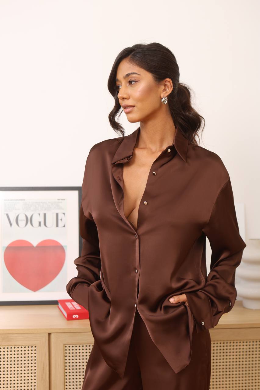 Woman wearing a brown satin shirt with a blurred background