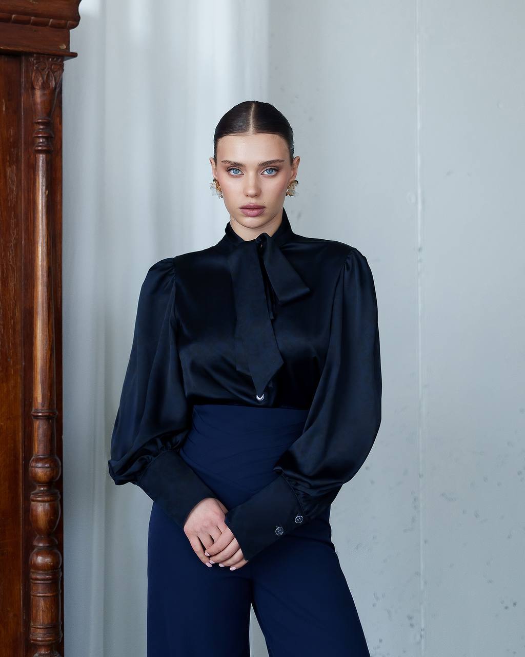 Woman wearing a dark blue outfit against a light gray background