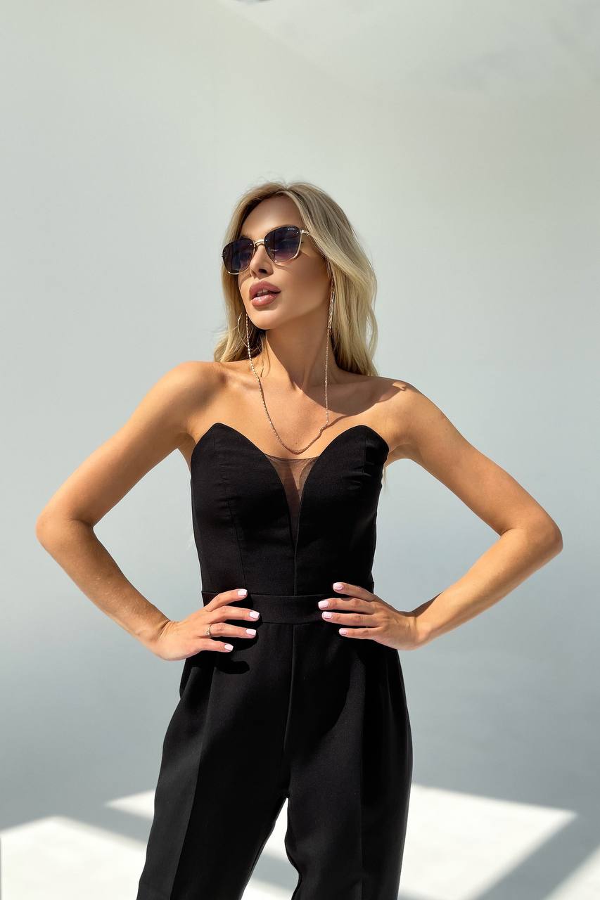 Woman wearing a black strapless jumpsuit against a light background