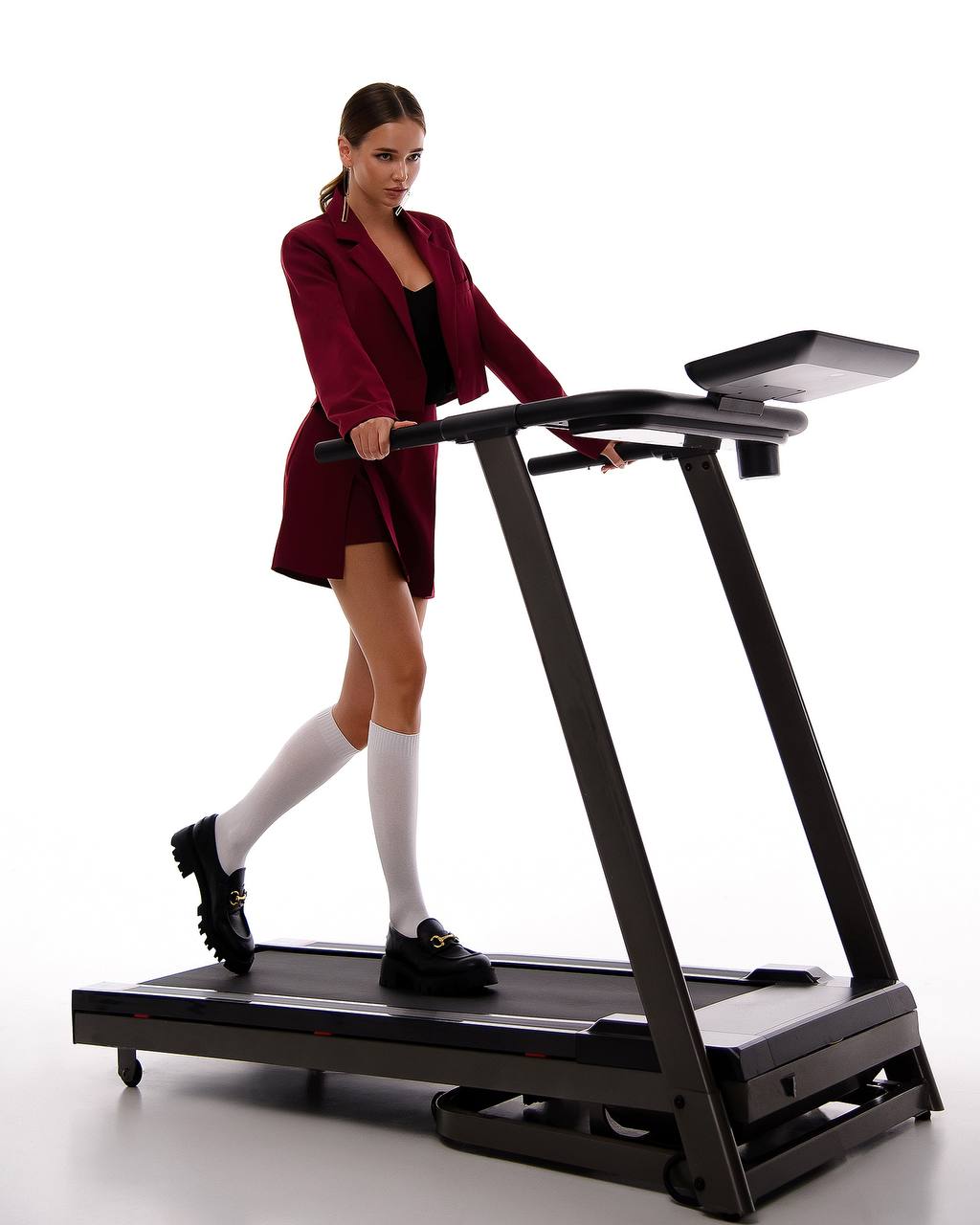 Woman in a red coat using a treadmill on a white background
