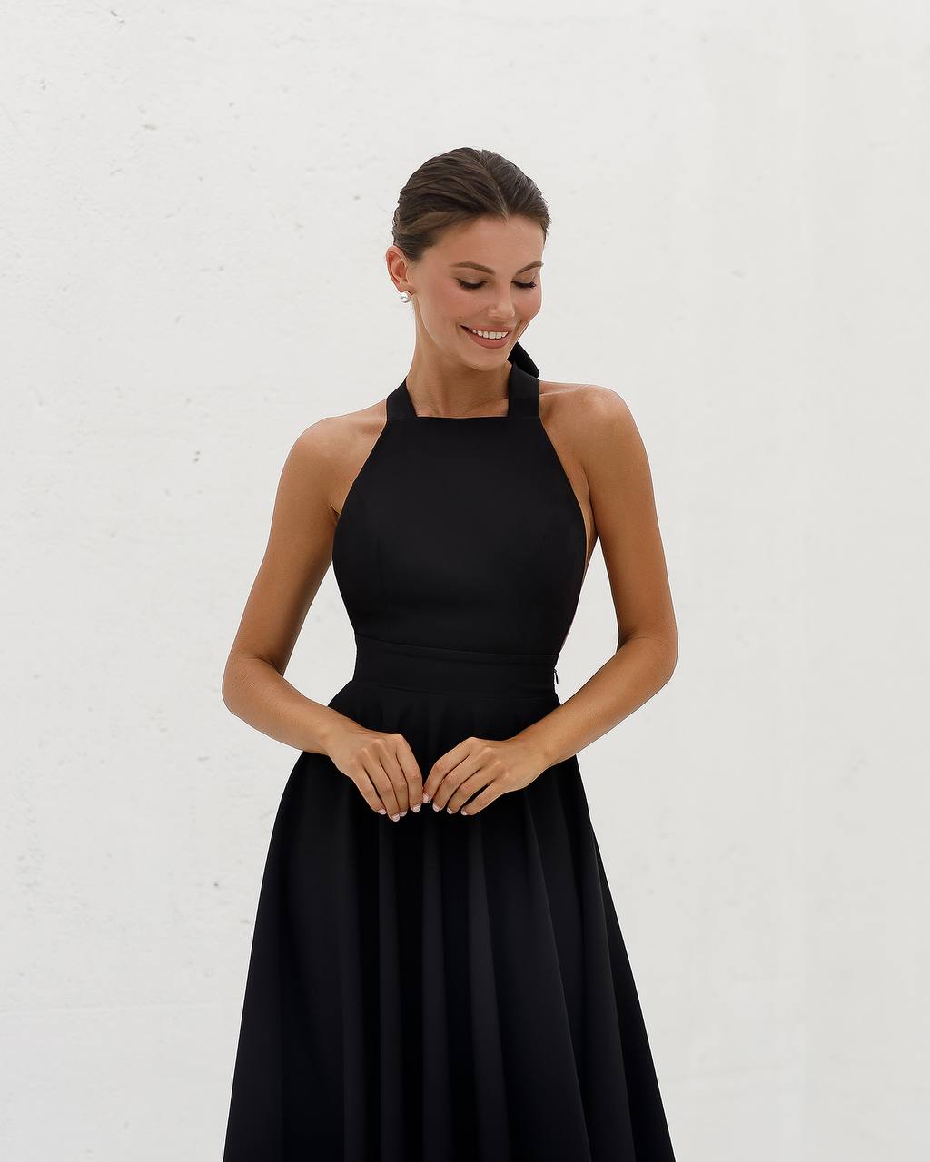 Woman wearing a black halter neck dress against a white background