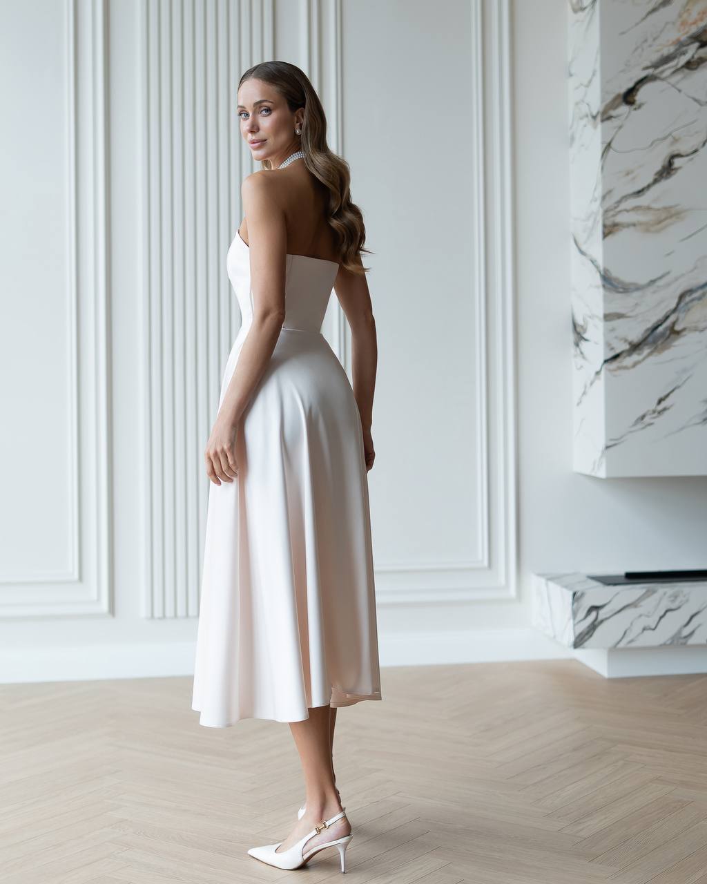 Woman in a white dress standing in a stylish interior setting