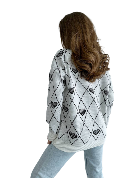 Person wearing a white sweater with black heart patterns on a white background