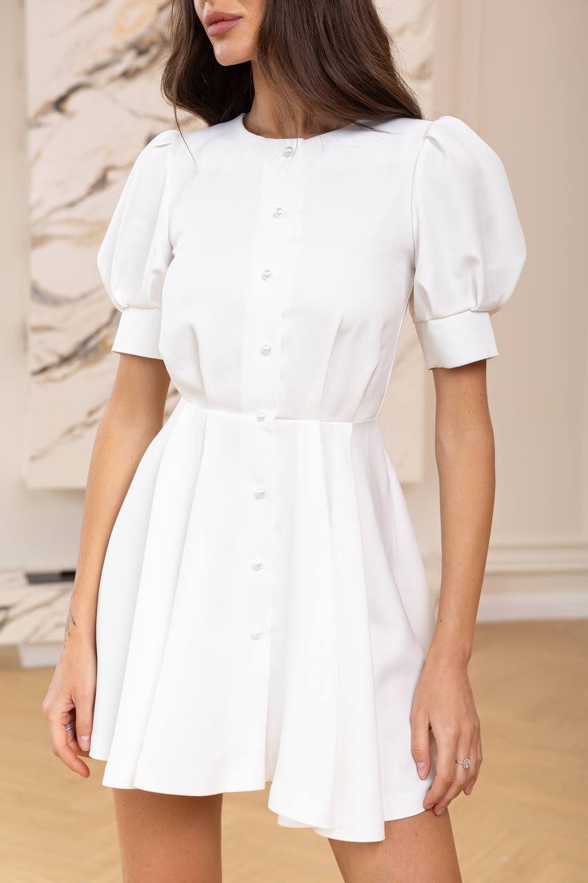 White dress with puff sleeves worn by a person against a neutral background