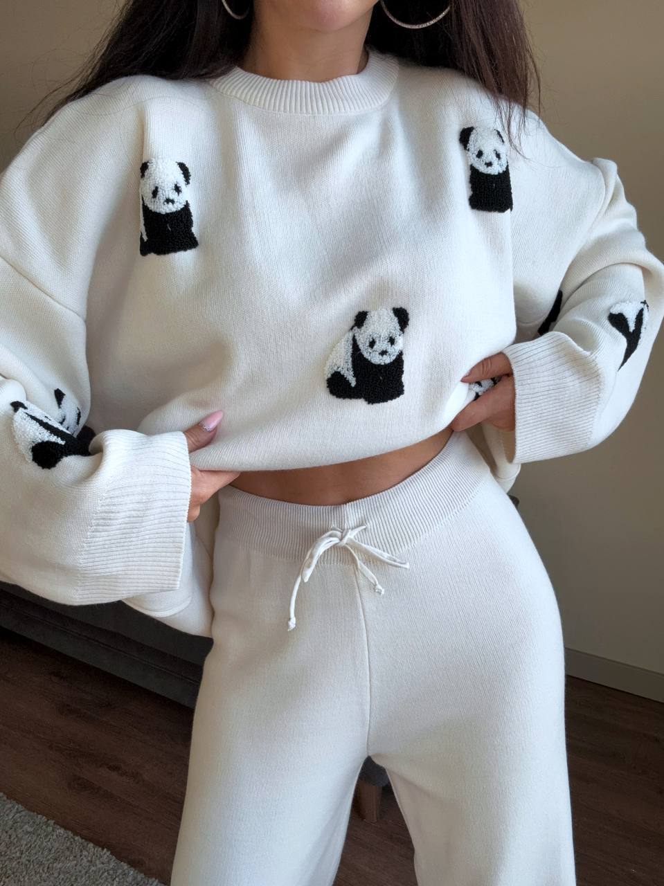 White sweater with panda designs worn by a person, paired with white pants.