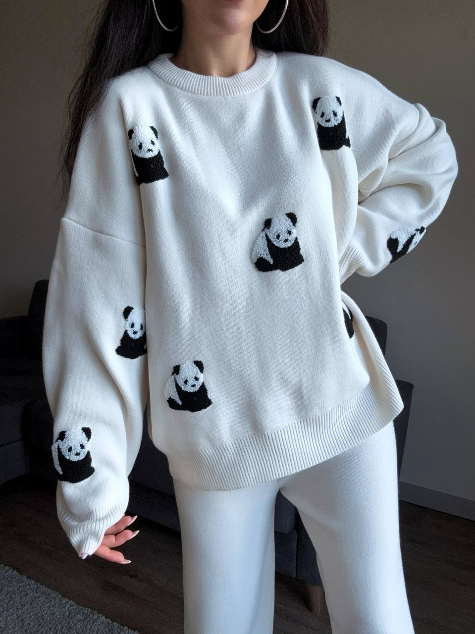 White sweater with panda patterns worn by a person indoors.