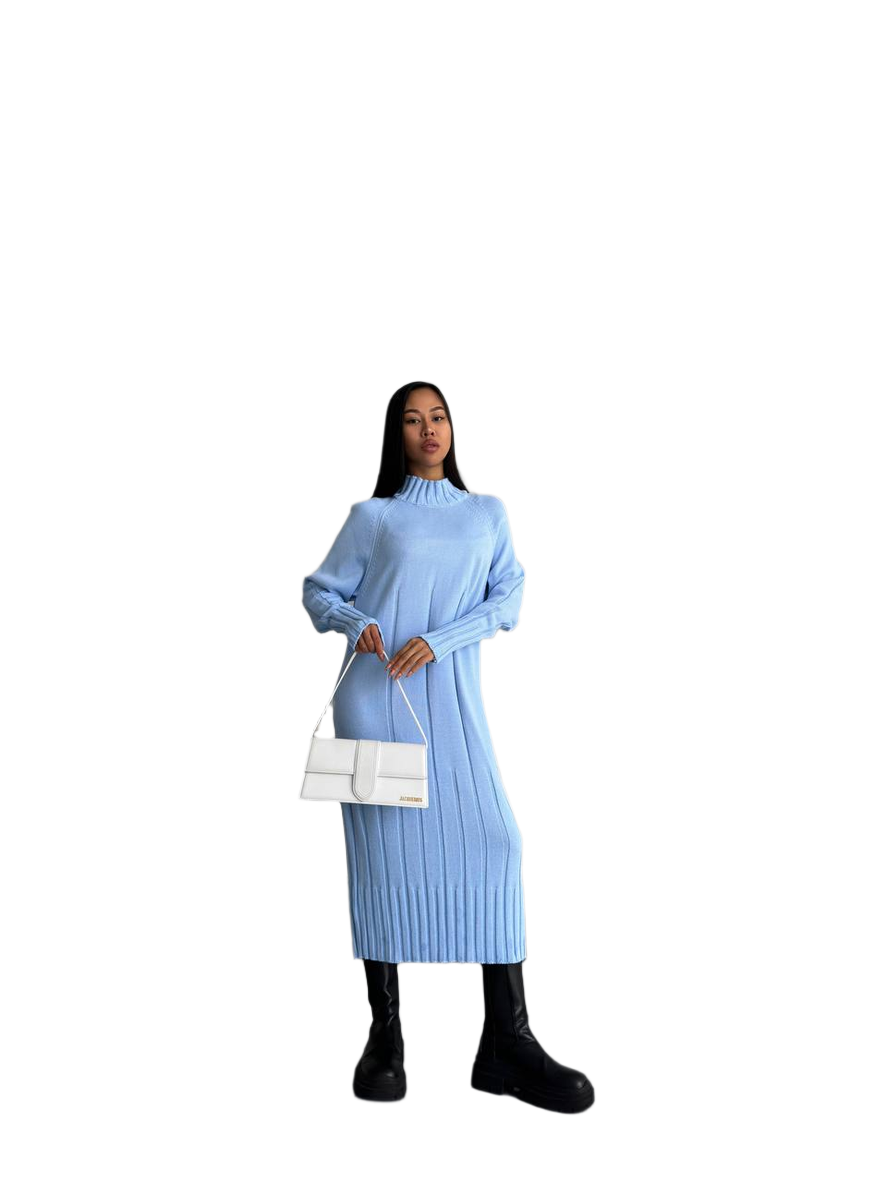 Woman wearing a light blue ribbed dress holding a white handbag on a white background