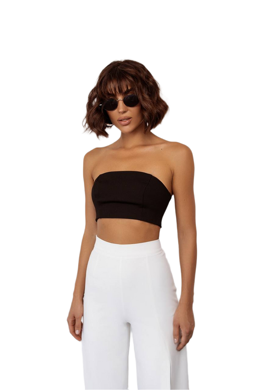 Woman wearing a black strapless top and white pants on a white background