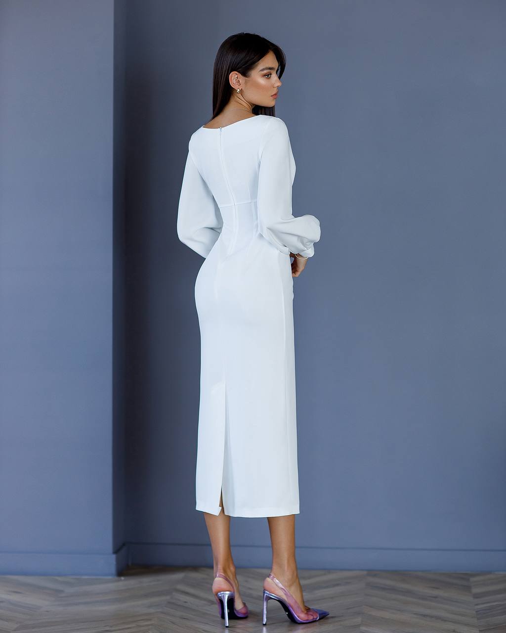 Woman wearing a white dress against a gray wall