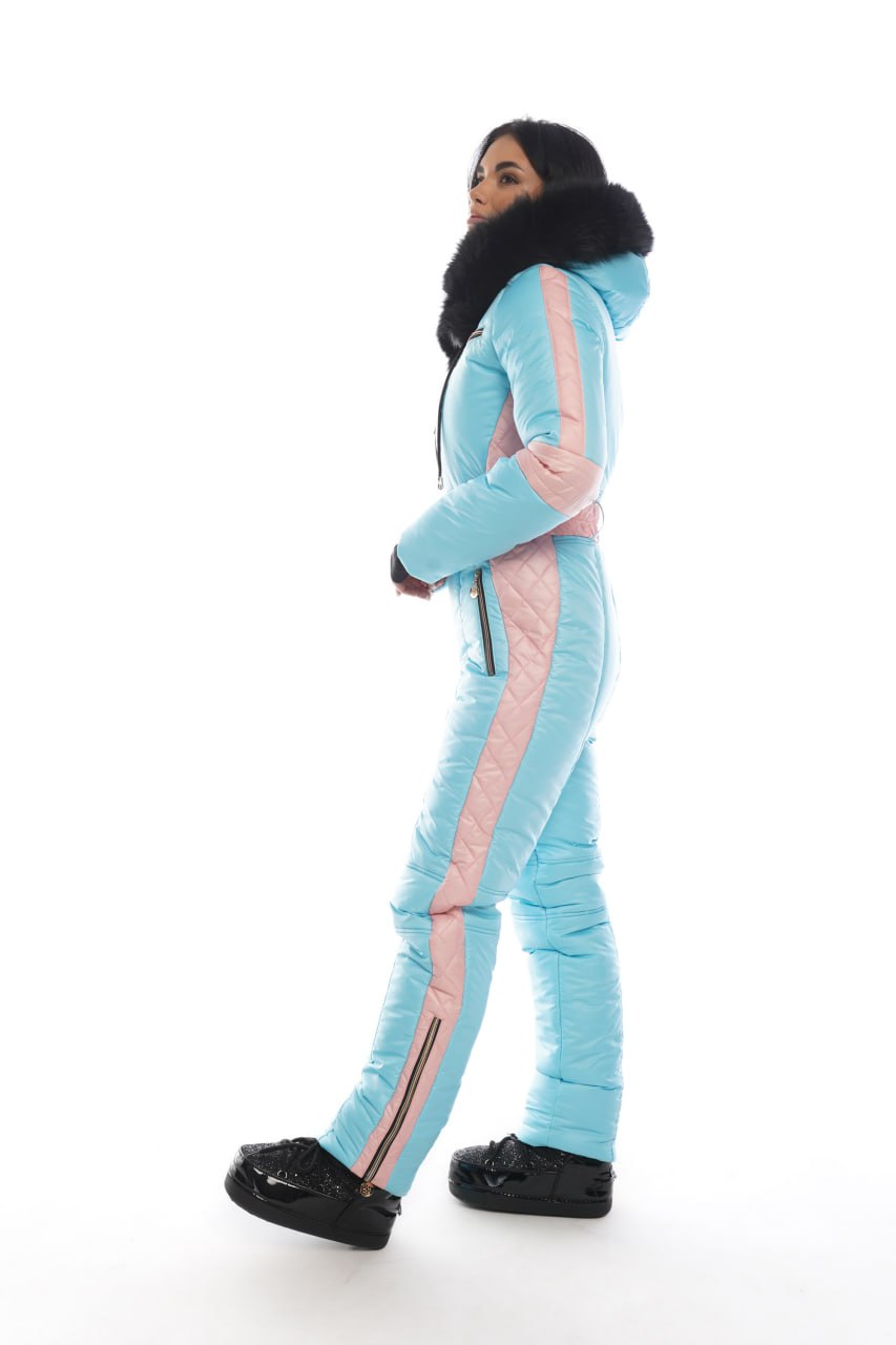 Person wearing a light blue and pink snowsuit with black shoes on a white background