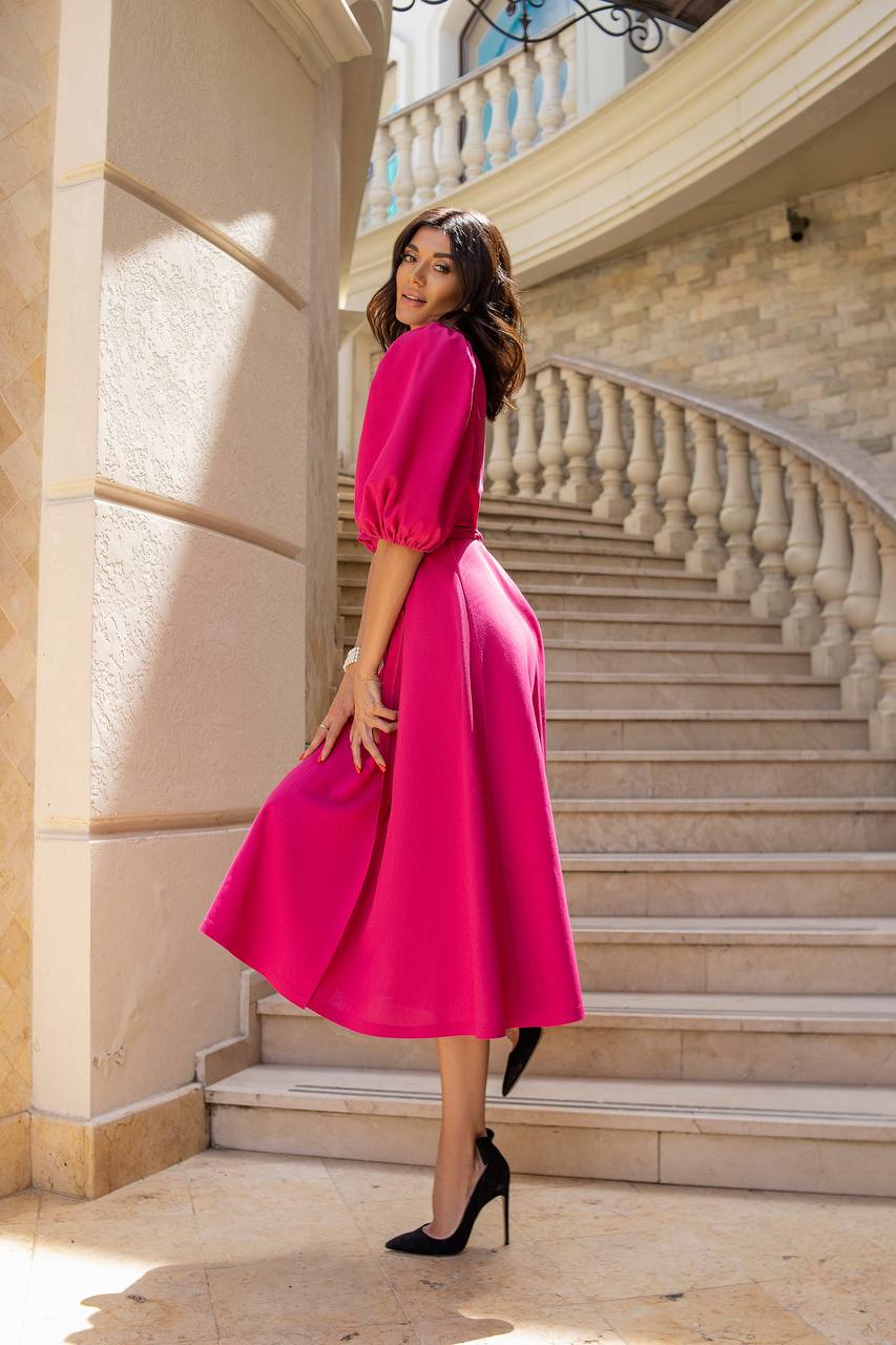 Woman in a bright pink dress standing on a staircase