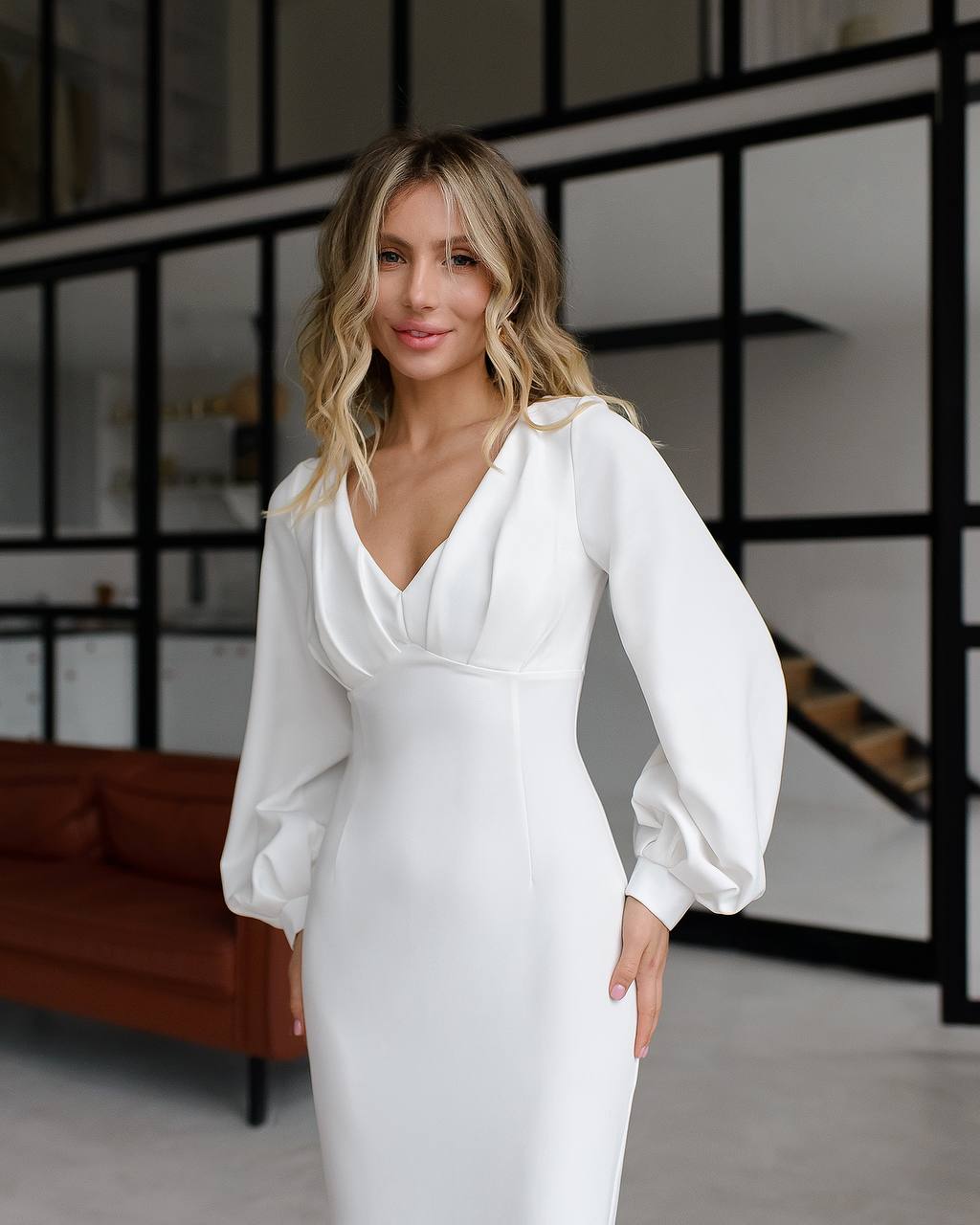 Woman wearing a white dress with puffed sleeves in an indoor setting.