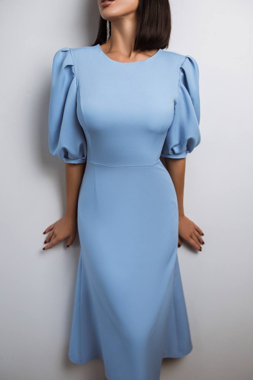 Woman wearing a light blue dress with puffed sleeves against a white background