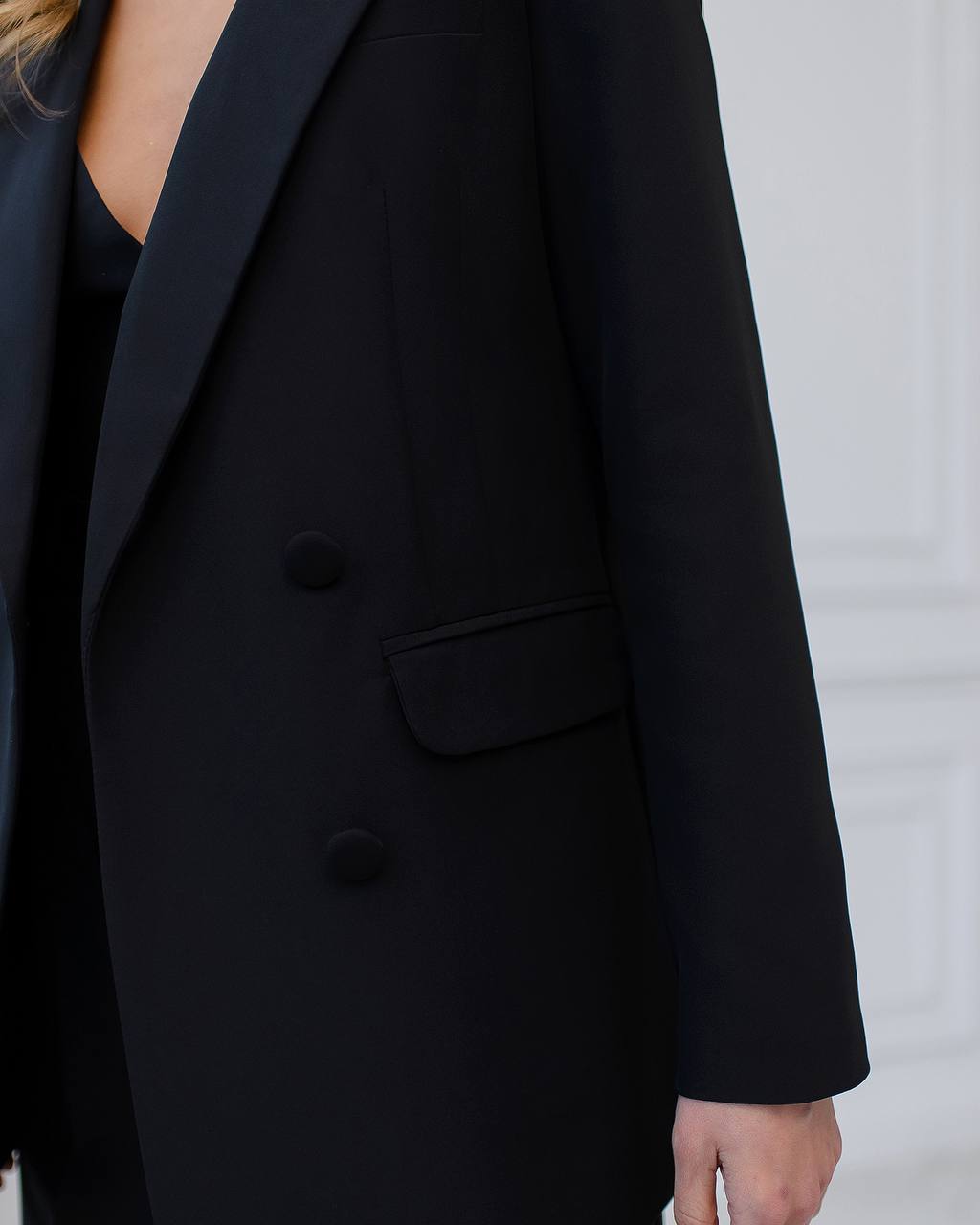 Black blazer worn by a person on a light gray background