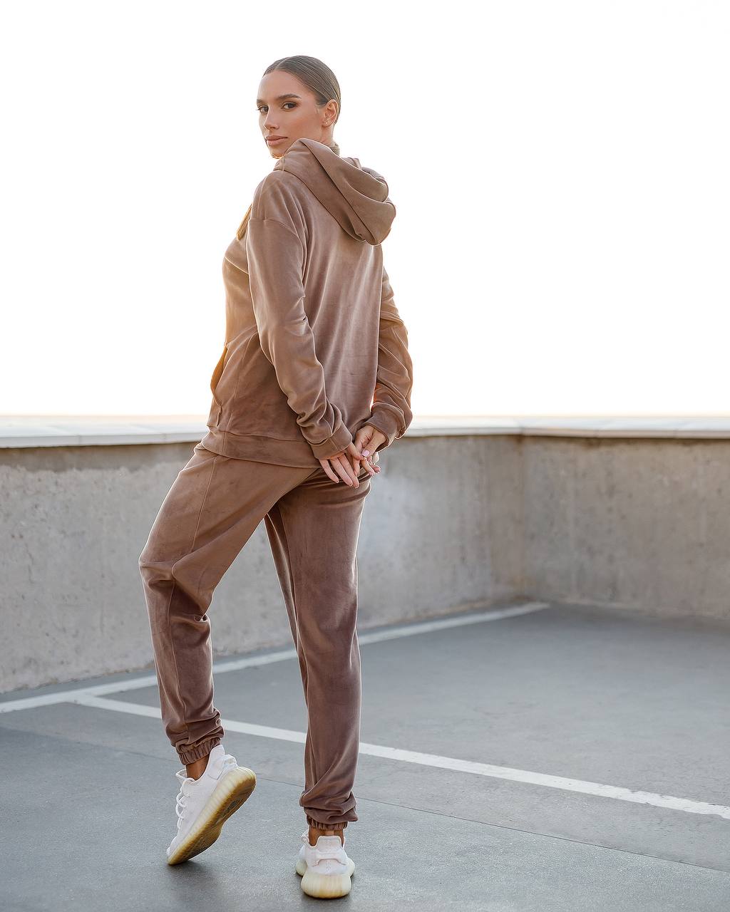 Person wearing a brown tracksuit standing on a rooftop.