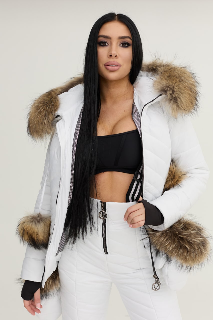 Woman wearing a white parka with fur trim against a plain background