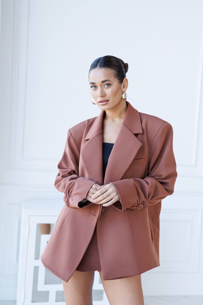 Woman wearing a brown blazer over a black top against a white background