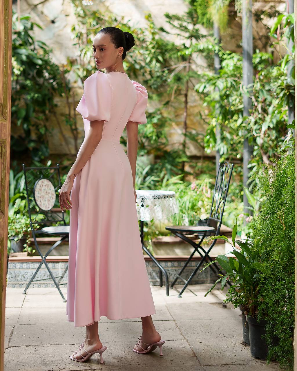 Woman in a pink dress standing in a garden setting