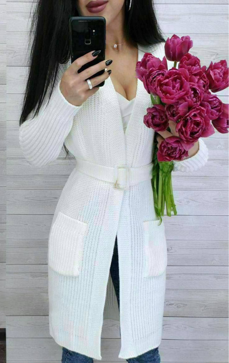Person wearing a white sweater holding a bouquet of pink flowers.