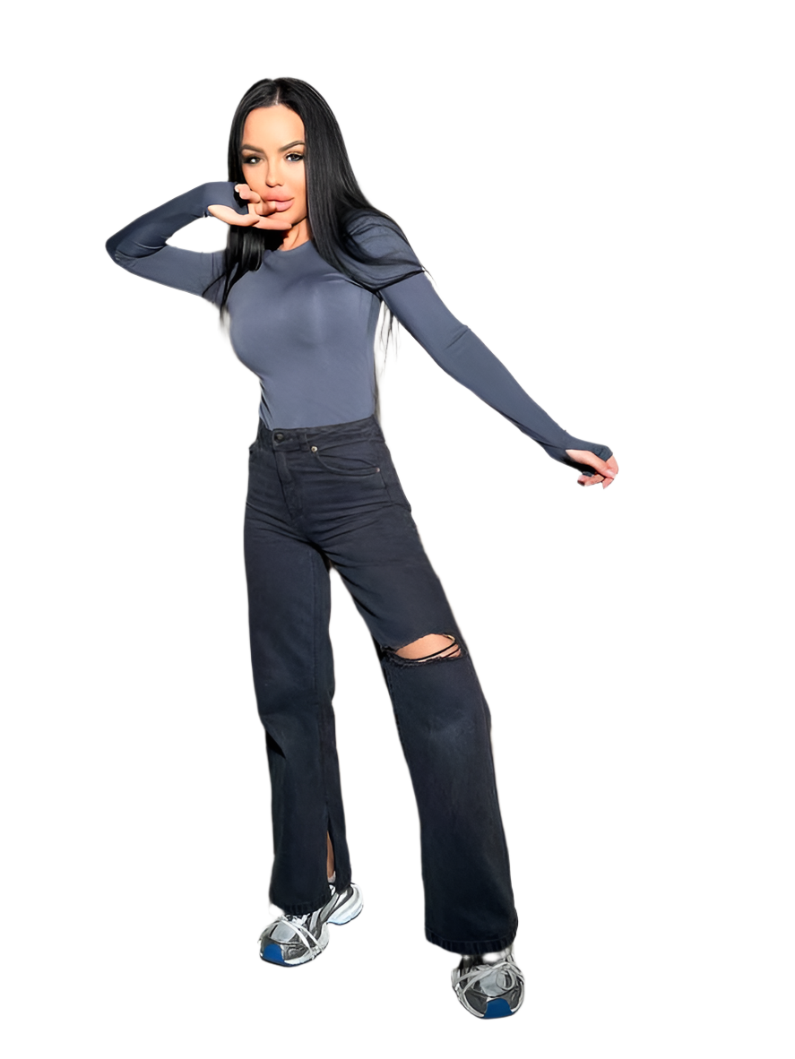 Woman wearing a gray long-sleeve top and black ripped jeans on a white background