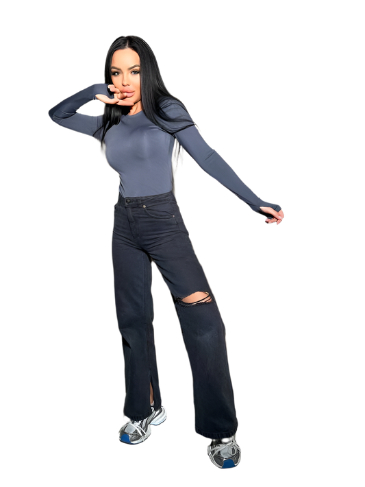 Woman wearing a gray long-sleeve top and black ripped jeans on a white background