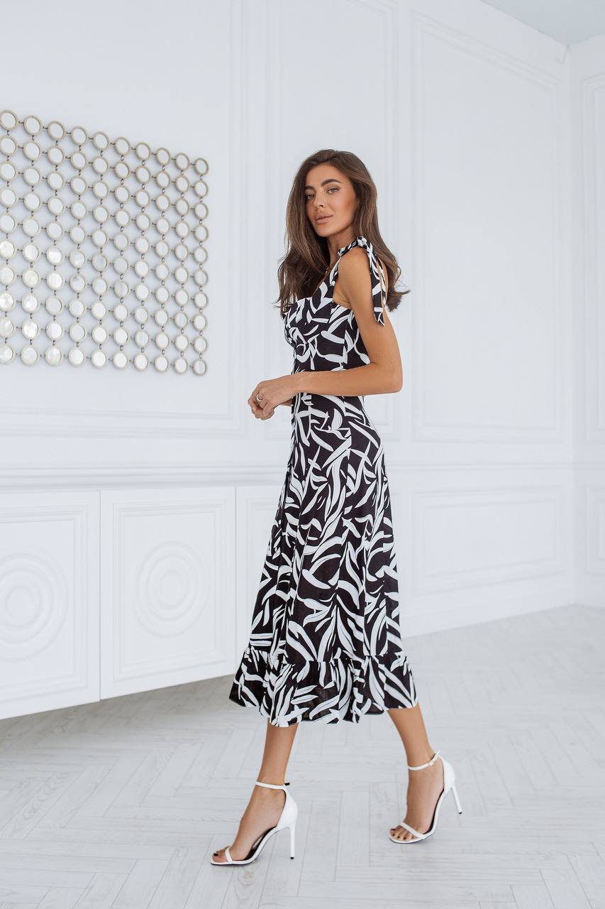 Woman wearing a black and white patterned dress in a minimalistic room.