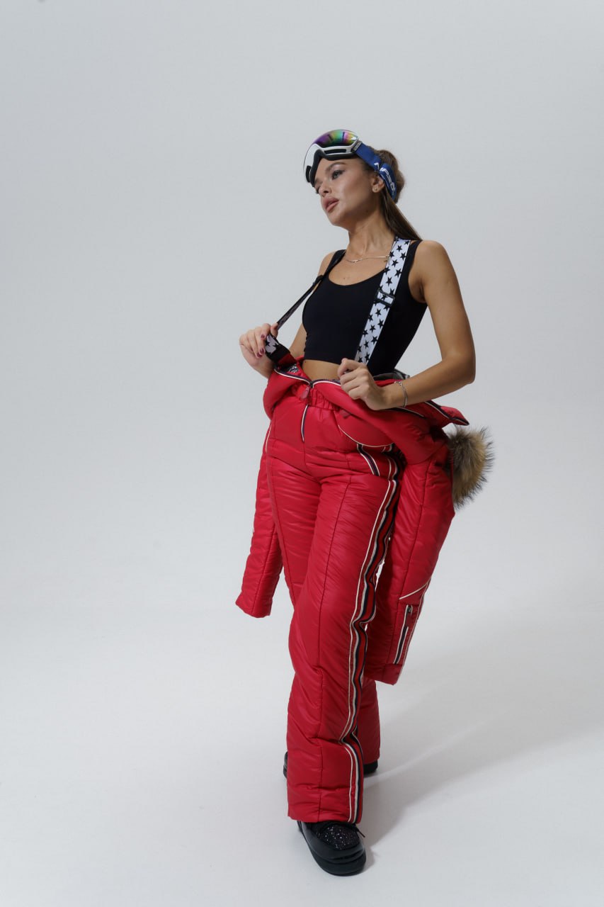 Woman wearing a black top and red puffer pants with a white background