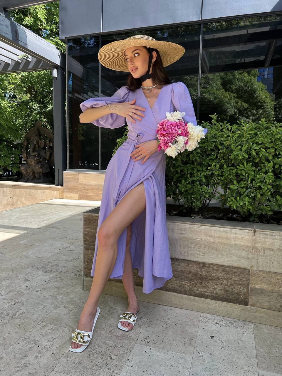 Woman in a lavender dress holding flowers outdoors